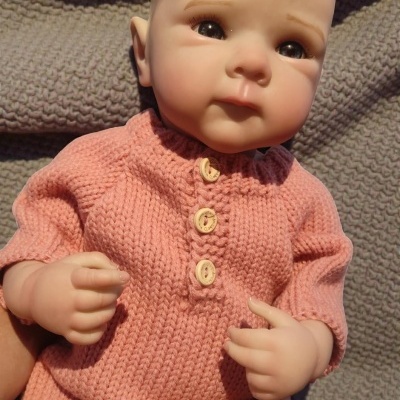 Boneca realista de bebé com roupa de malha cor de rosa e botões de madeira