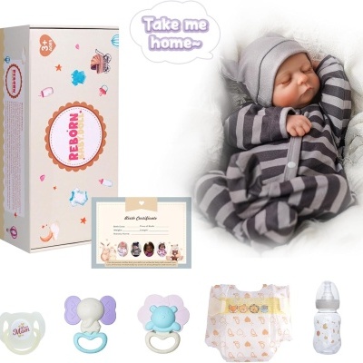 Boneca recém-nascida com pijama às riscas cinzentas, embalagem e acessórios como chupetas, fraldas e biberão.