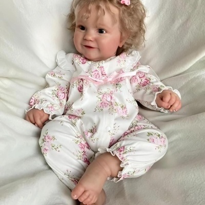 Boneca realista com macacão floral sentada em tecido branco