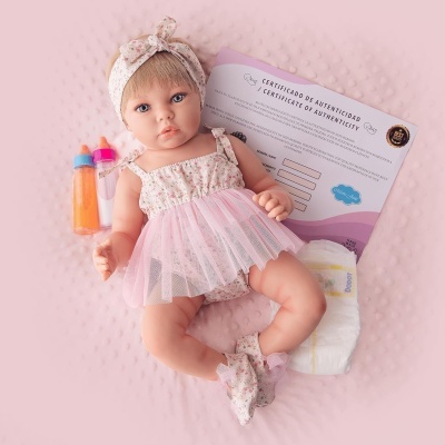 Boneca bebé realista com vestido floral rosa e branco, biberões coloridos, fralda branca e certificado de autenticidade