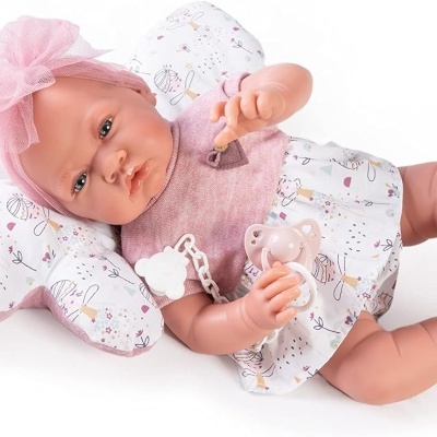 Boneca bebé realista com roupa rosa e branca deitada em almofada