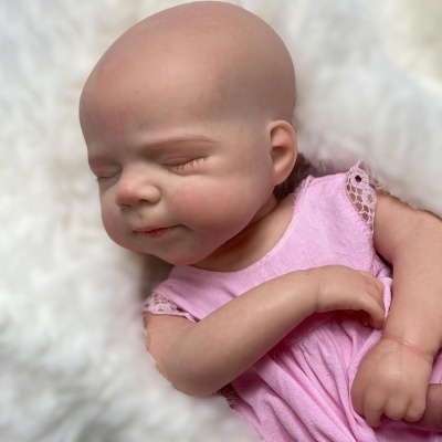 Boneca realista de bebé de silicone com vestido rosa deitada em tecido branco felpudo