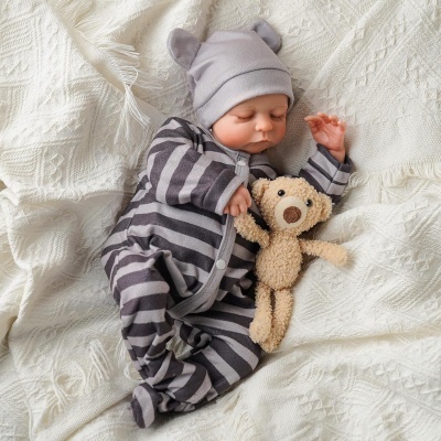 Bebé a dormir com pijama riscado cinzento e touca com orelhas segurando ursinho de peluche