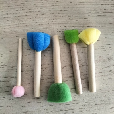 Cinco pincéis de esponja coloridos sobre superfície de madeira