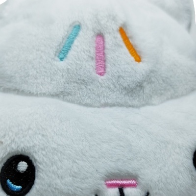 Boneco de peluche branco com olhos bordados e linhas coloridas na cabeça