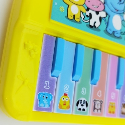 Teclado de brinquedo amarelo com teclas coloridas e desenhos de animais