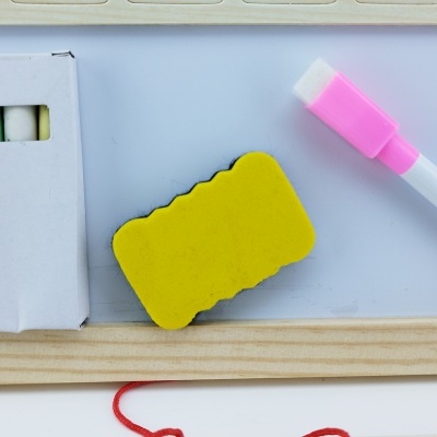 Itens de quadro branco com giz, esponja e marcador em superfície branca com borda de madeira