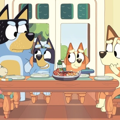 Desenho animado de quatro cães sentados à mesa com comida numa cozinha clara