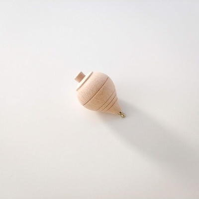 pião de madeira claro com linhas circulares sobre fundo branco