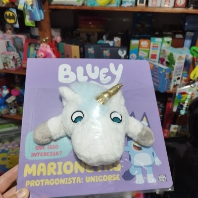 Marioneta de unicórnio em peluche branca com chifre dourado embalada em cartão roxo