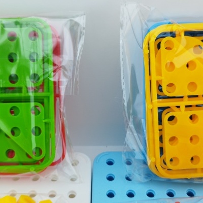 Peças de construção verdes e amarelas em embalagens transparentes sobre base azul