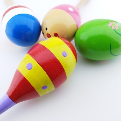 Quatro maracas de madeira coloridas com padrões e desenhos variados