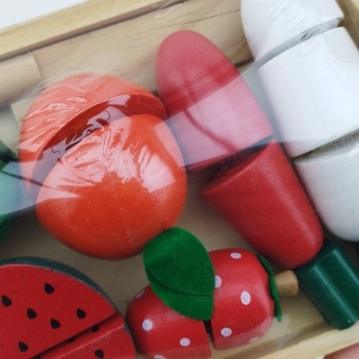 Brinquedos de madeira coloridos em forma de frutas e legumes numa caixa de madeira