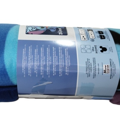 Manta de padrão colorido embalada com faixa azul claro com texto e símbolos