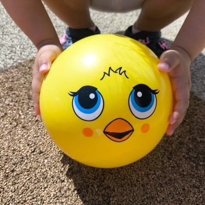 Bola amarela com rosto de desenho animado segurada por criança