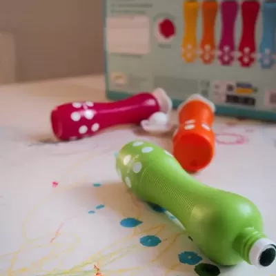 Tubos de tinta colorida em plástico sobre papel com desenhos de tinta colorida.