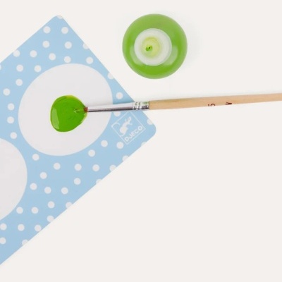 Pincel de pintura com tinta verde, palete azul com bolinhas brancas e tigela verde de tinta