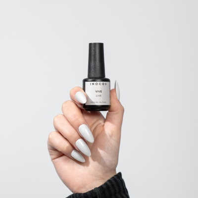 Mão com unhas brancas segurando frasco de verniz gel INOCOS VIVE