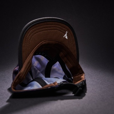 Boné castanho e preto com figura branca bordada e alça ajustável