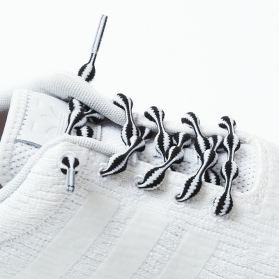 Ténis desportivo branco com atacadores pretos e brancos e tecido tricotado