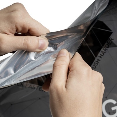 Mãos a descolar película prateada de superfície preta brilhante com texto