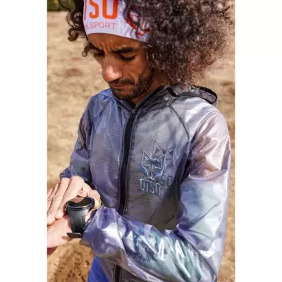 Homem usa jaqueta impermeável cinza translúcida com logotipo de raposa e faixa de cabeça branca e laranja