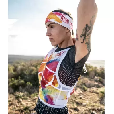 Pessoa a usar pulseira e colete desportivo multicoloridos com texto UTSA ULTRA TRAIL SPAIN em ambiente natural