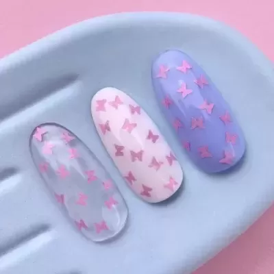 Unhas postiças decorativas com borboletas cor-de-rosa sobre prato azul claro