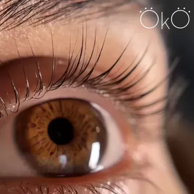 Close-up de olho castanho com cílios longos e texto ÖkÖ no canto