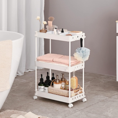 Carrinho branco de três níveis com artigos de banho e toalhas numa casa de banho moderna