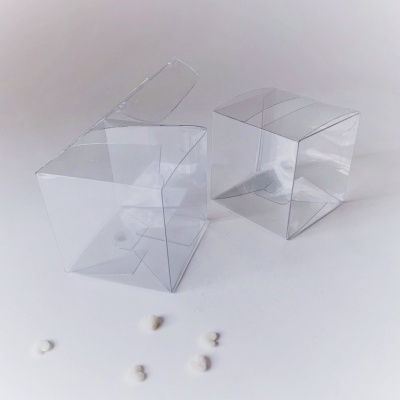 Duas caixas transparentes de plástico rígido sobre superfície branca com pequenos objetos brancos