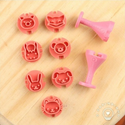 Conjunto de carimbos de silicone rosa com desenhos de animais sobre madeira clara