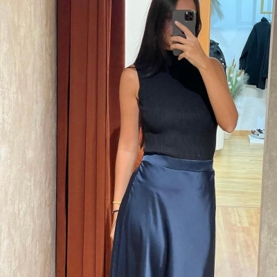 Pessoa a tirar selfie de roupa com top preto e saia azul em espelho interior