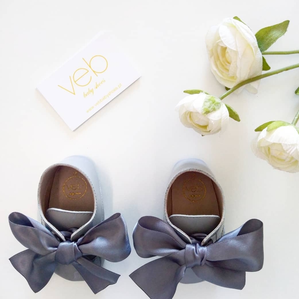 sapatinhos de bebé brancos com laços cinzentos e flores brancas