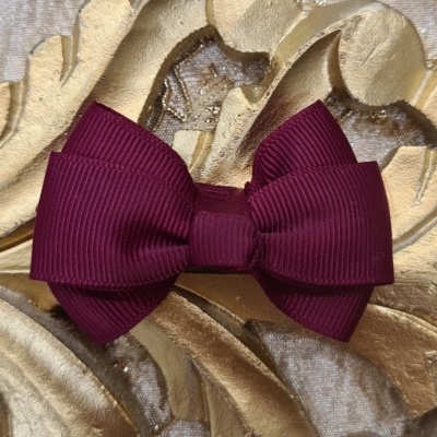 Laço de cabelo bordô em tecido canelado sobre superfície dourada decorativa