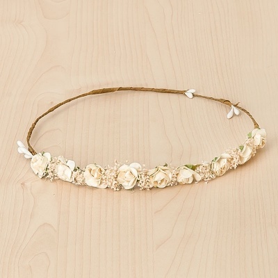 Coroa de flores creme e bege num fundo de madeira clara