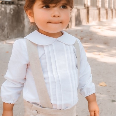 Criança com roupa formal branca e bege em ambiente externo