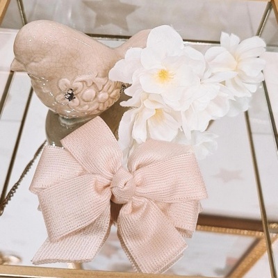 Coração decorativo, flores brancas artificiais e laço rosa claro sobre caixa espelhada dourada