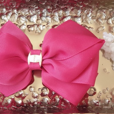 Laço rosa fúcsia com detalhe metálico sobre fundo texturizado prateado e flores