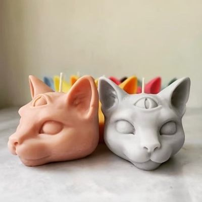 Velas em forma de cabeça de gato de cor bege e branca com terceiro olho