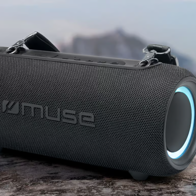 Coluna portátil preta cilíndrica com anel azul e alça sobre rocha com montanhas ao fundo