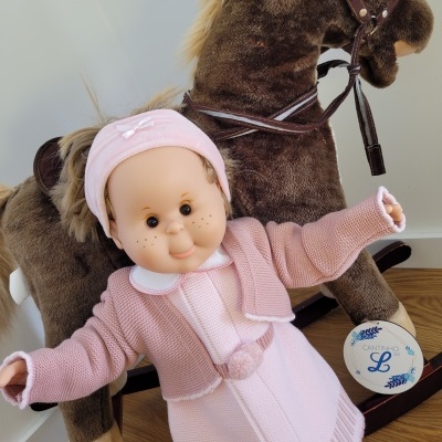 Boneca de roupinha rosa com cavalo de balanço de pelúcia castanho