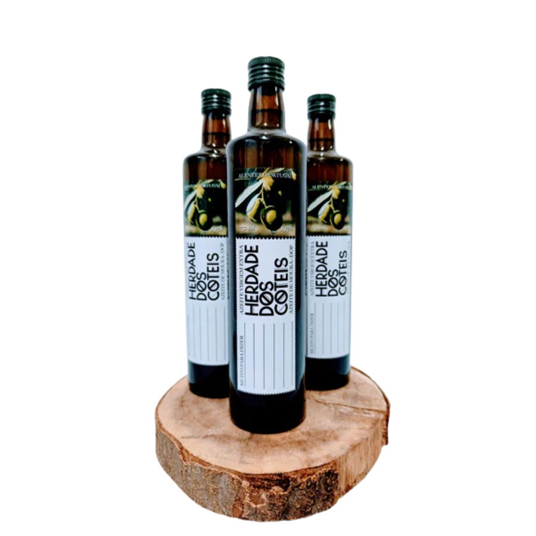 Três garrafas de azeite HERDADE DOS COTES em vidro castanho sobre um tronco de madeira