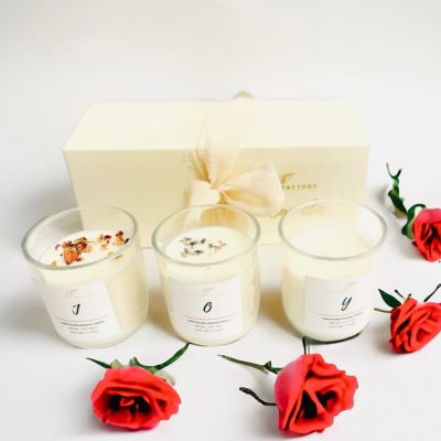 Conjunto de três velas aromáticas em copos de vidro com laço e rosas vermelhas