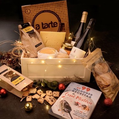 Cesta de presente gastronômica com queijo, vinho, café e livro numa caixa de madeira com luzes decorativas
