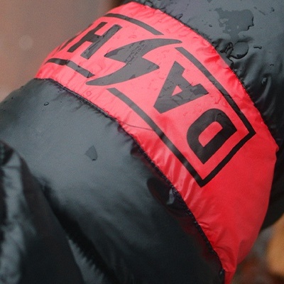 Manga preta almofadada com faixa vermelha e texto 'DAS' em preto