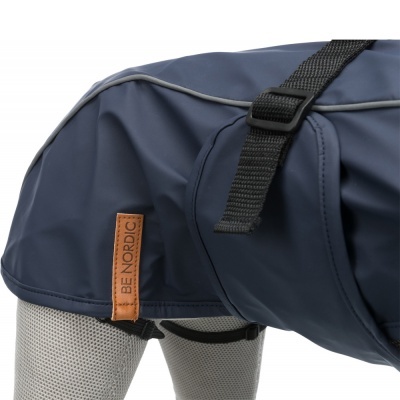 Casaco impermeável azul para cão com etiqueta BE NORDIC e alças pretas numa manequim cinza