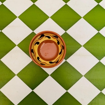 Prato de cerâmica amarelo e preto sobre azulejos verde e branco