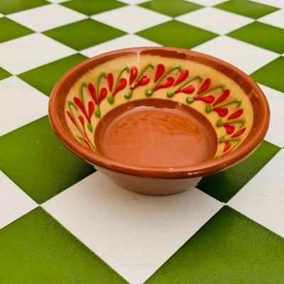 tigela cerâmica com padrão vermelho e verde em superfície de azulejos xadrez verde e branco