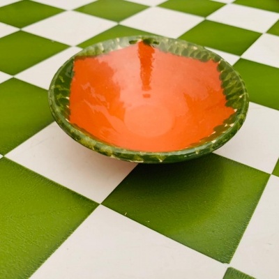 prato laranja com borda verde sobre mesa xadrez verde e branca